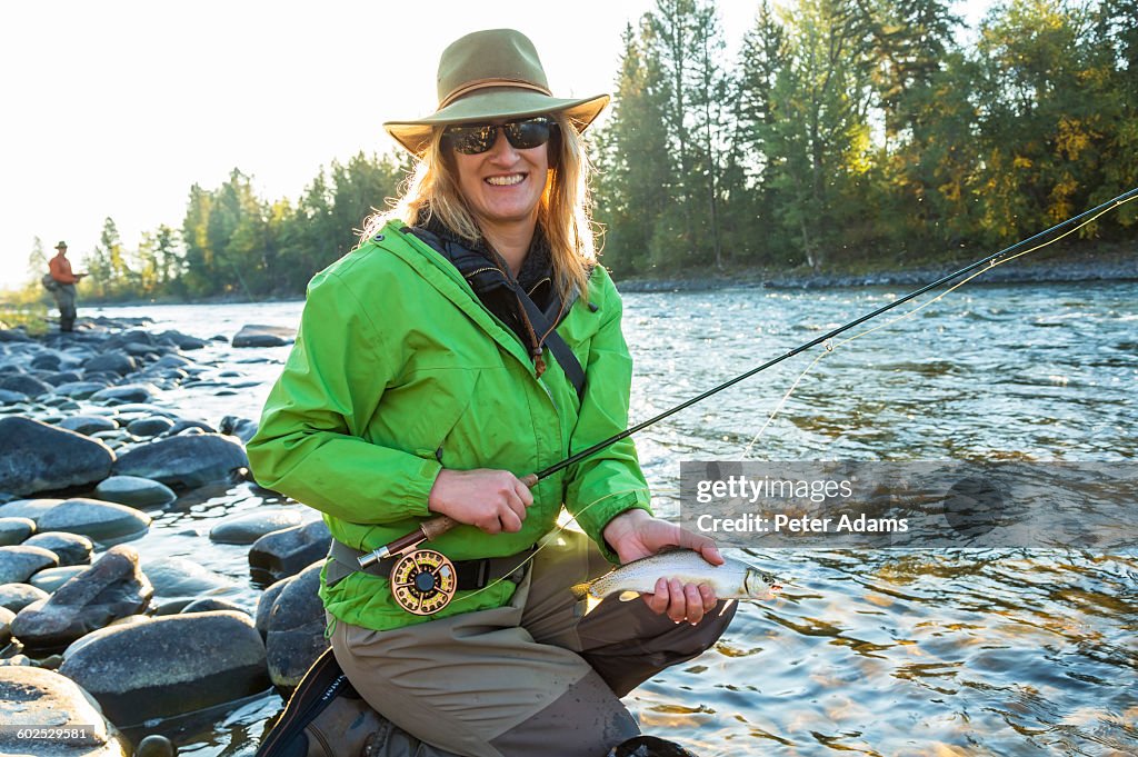 Woman fly fishing, rod & line caught trout, Canada