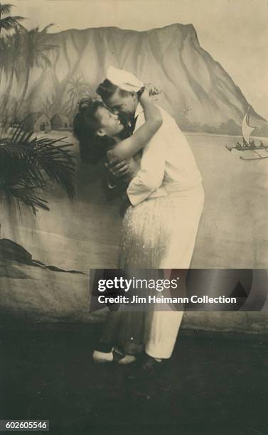 Sailor hugging woman wearing hula skirt in arcade photo depicting Diamondhead.