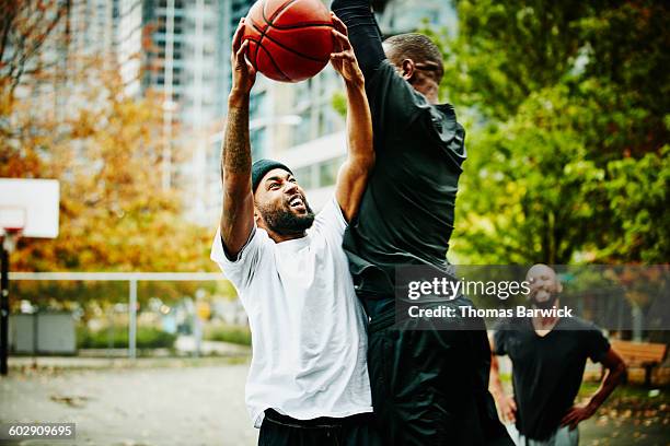 basketball player taking shot while being blocked - basketball blocking shot stock pictures, royalty-free photos & images