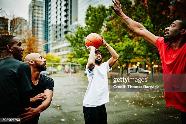 basketball player preparing to shoot over defender - basketball blocking shot stock pictures, royalty-free photos & images