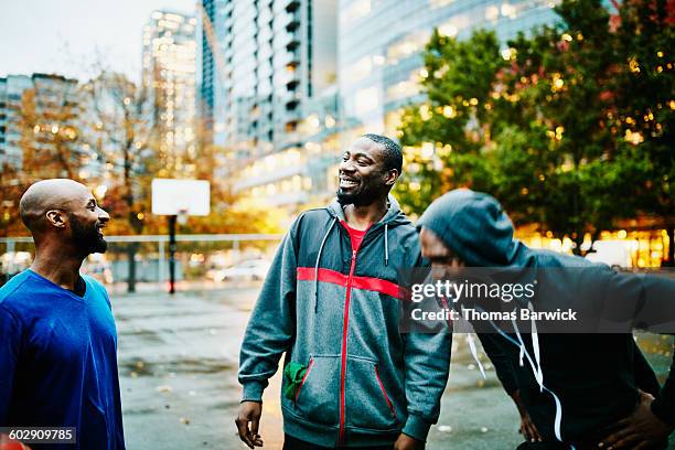 laughing friends on basketball court before game - african american basketball stock pictures, royalty-free photos & images