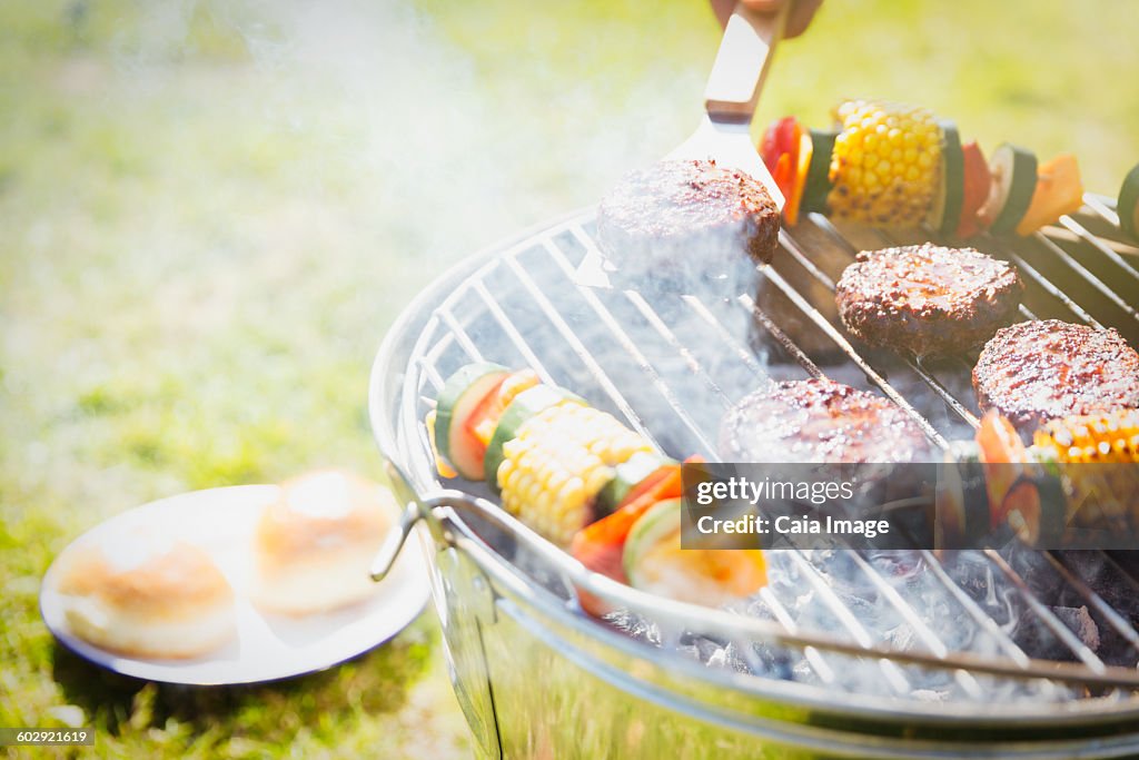 Hamburgers and vegetable skewers on barbecue grill