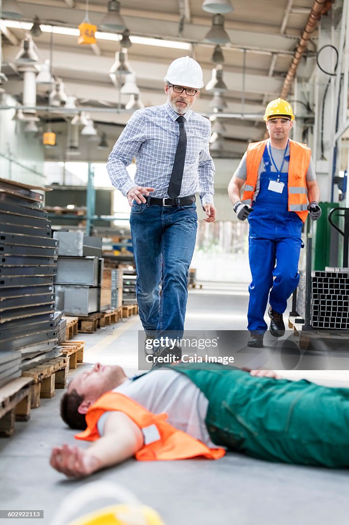 Workers running toward fallen coworker unconscious on factory floor