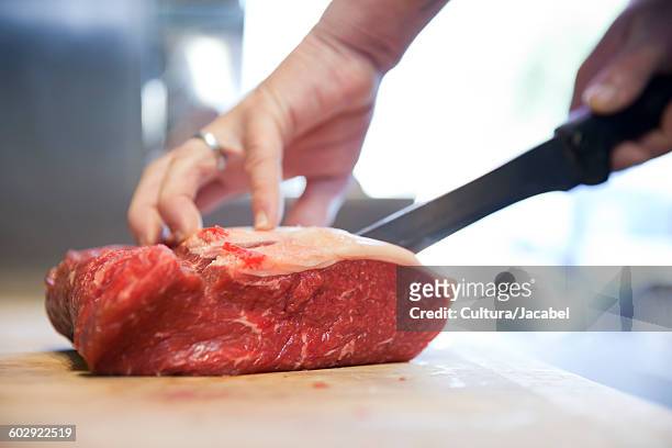close up of butchers hands slicing raw steak on butchers block - butcher stock pictures, royalty-free photos & images