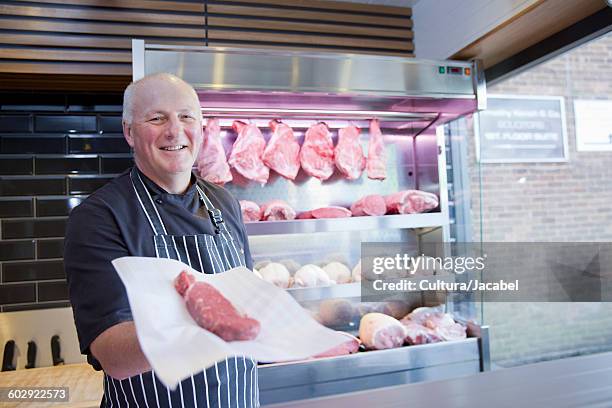 portrait of butcher holding steak in butchers shop - butcher portrait imagens e fotografias de stock