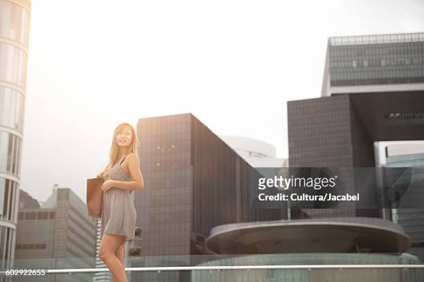 young woman walking beside harbour, hong kong, china - cultura orientale photos et images de collection