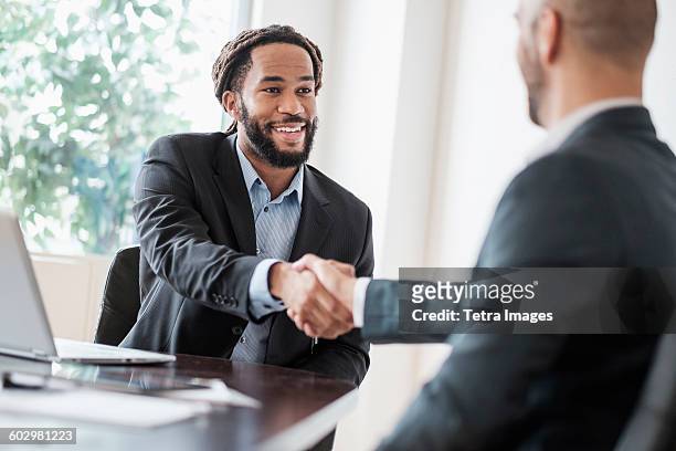 smiling businessmen shaking hands in office - dela ut kort bildbanksfoton och bilder