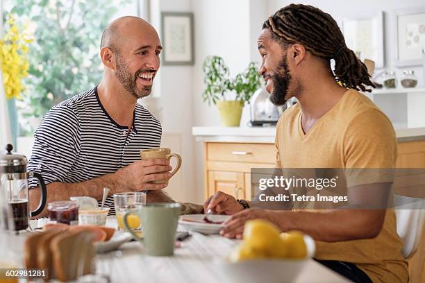 smiley homosexual couple having breakfast in kitchen - black mug stock pictures, royalty-free photos & images