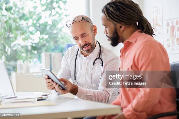 doctor giving consultation to patient using digital tablet - male medical professional stock pictures, royalty-free photos & images