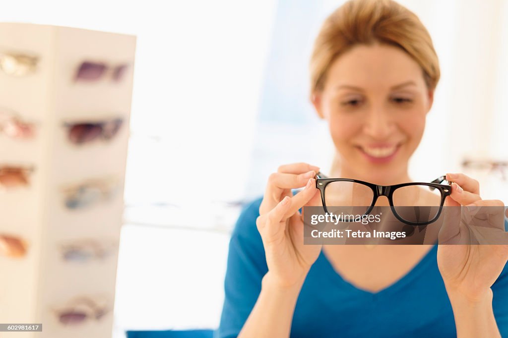 Woman and choosing eyeglasses in store