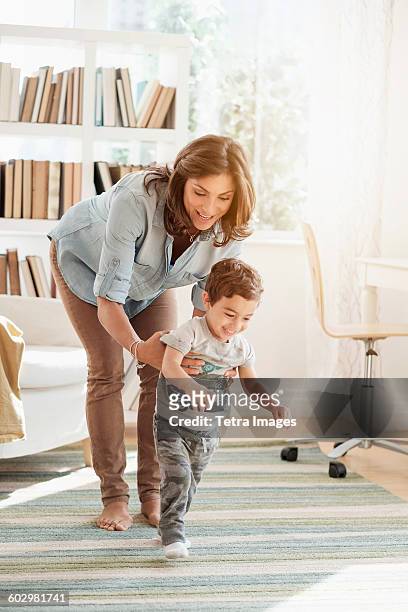mother holding son (2-3) making first steps - primi passi foto e immagini stock