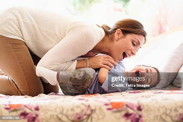 mother playing with son (2-3) on bed - tickling stock-fotos und bilder