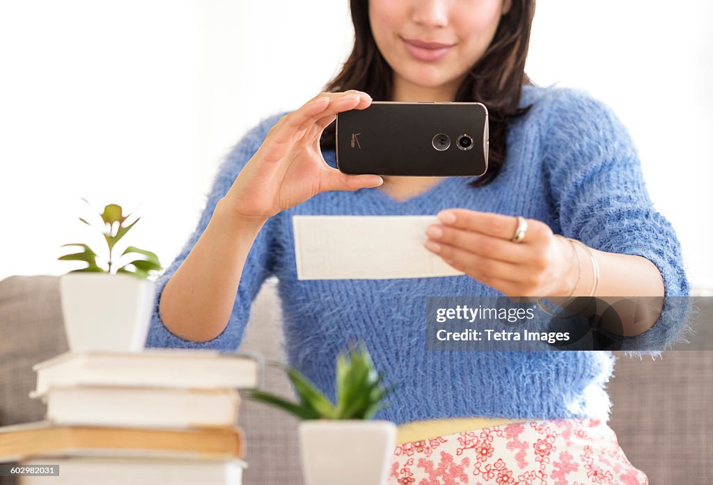 Young woman photographing bank statement