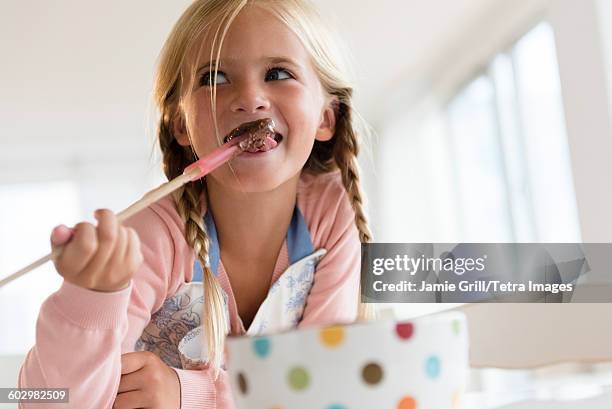 girl (6-7) eating chocolate - girl baking stock pictures, royalty-free photos & images