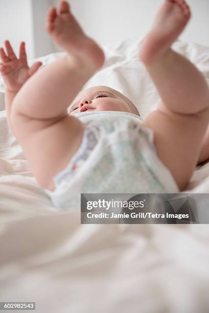 baby girl (12-17 months) lying down with legs up - barefoot feet up lying down girl stock-fotos und bilder