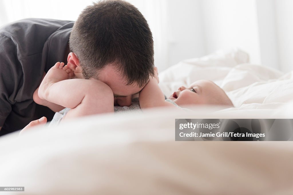 Father kissing baby daughter (12-13 months) belly