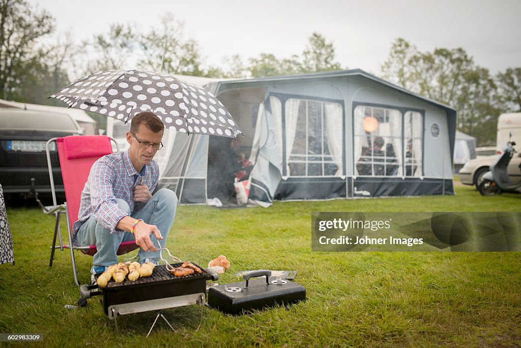 Man barbecuing in rain
