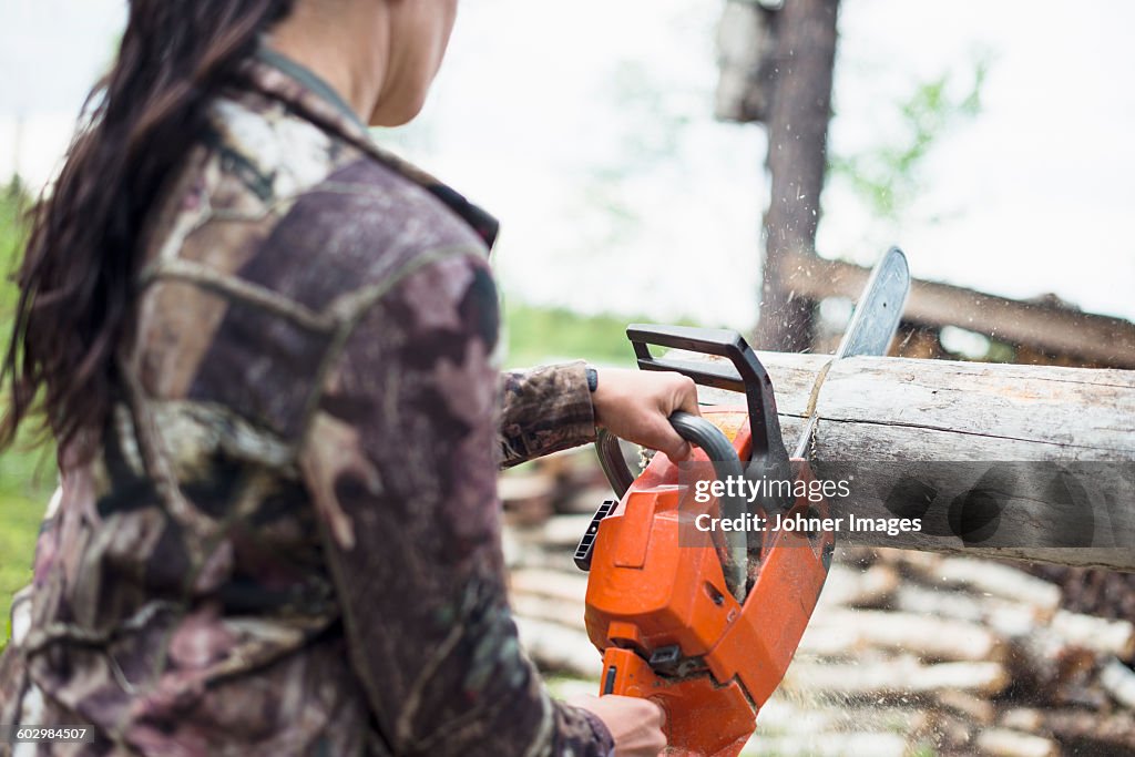 Woman using chainsaw