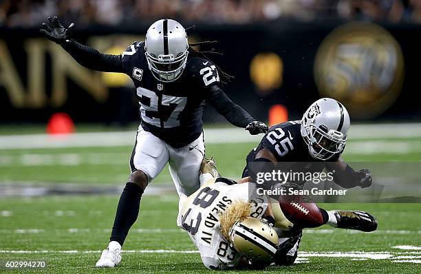 Hayden of the Oakland Raiders and Reggie Nelson strip the ball from Willie Snead of the New Orleans Saints during the fourth quarter at Mercedes-Benz...