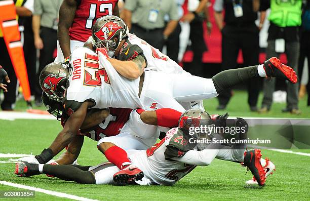 Devonta Freeman of the Atlanta Falcons is tackled by Lavonte David, Brent Grimes, and Chris Conte of the Tampa Bay Buccaneers at the Georgia Dome on...