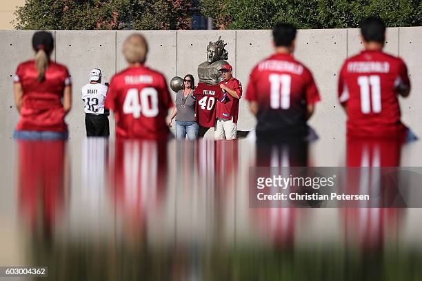 Fans pose in front of the Pat Tillman statue before the NFL game between the Arizona Cardinals and New England Patriots at the University of Phoenix...