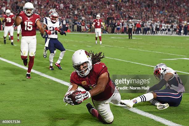 Wide receiver Larry Fitzgerald of the Arizona Cardinals dives in front of cornerback Logan Ryan of the New England Patriots to score a touchdown in...