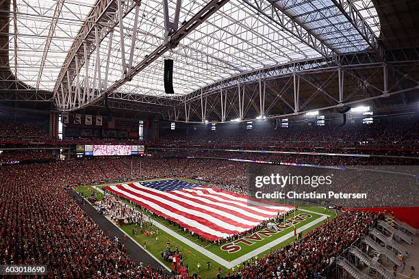 The american flag is draped across the field for the national anthem to the NFL game between the Arizona Cardinals and the New England Patriots at...