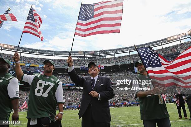 Rudy Guliani waves an American Flag flanked by former New York Jets players Marvin Jones, Laveranues Coles and Wayne Chrebet when he serves as...