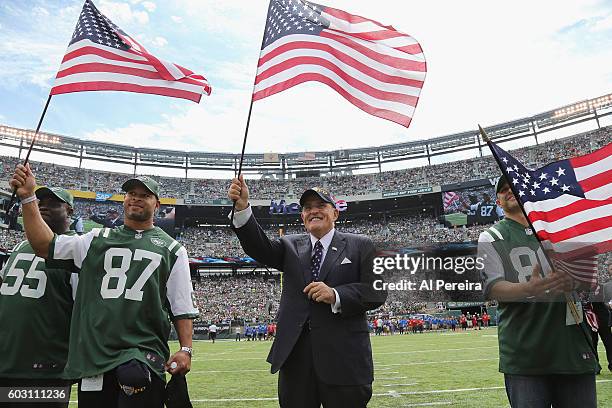Rudy Guliani waves an American Flag flanked by former New York Jets players Marvin Jones, Laveranues Coles and Wayne Chrebet when he serves as...