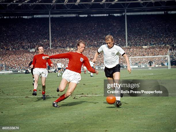 England defender Jack Charlton tackles Siegfried Held of West Germany watched by Nobby Stiles, during the World Cup Final against West Germany at...