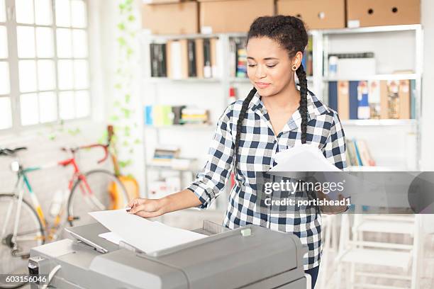 jeune assistant africain utilisant un photocopieuse sur le lieu de travail - imprimante photos et images de collection