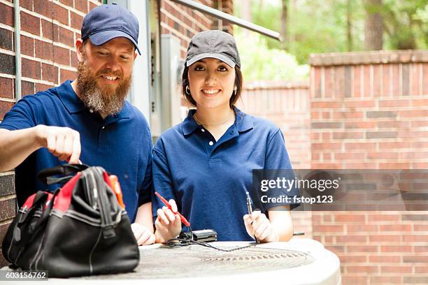 air conditioner repairmen work on home unit. - service technician stock pictures, royalty-free photos & images