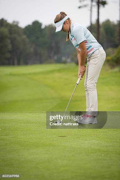 young female golfer hits a great putt - golfer putting stock pictures, royalty-free photos & images