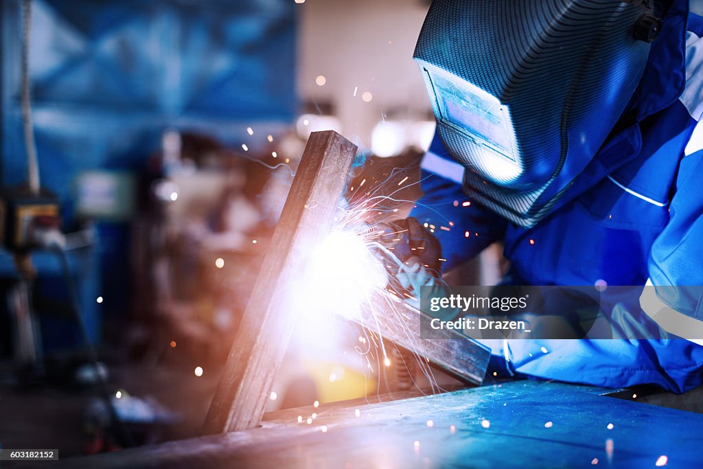 Professional welder in a factory welding steel bars