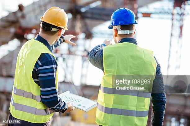 ingeniero y contratista que tienen una breve reunión en el sitio de construcción - bridge built structure fotografías e imágenes de stock