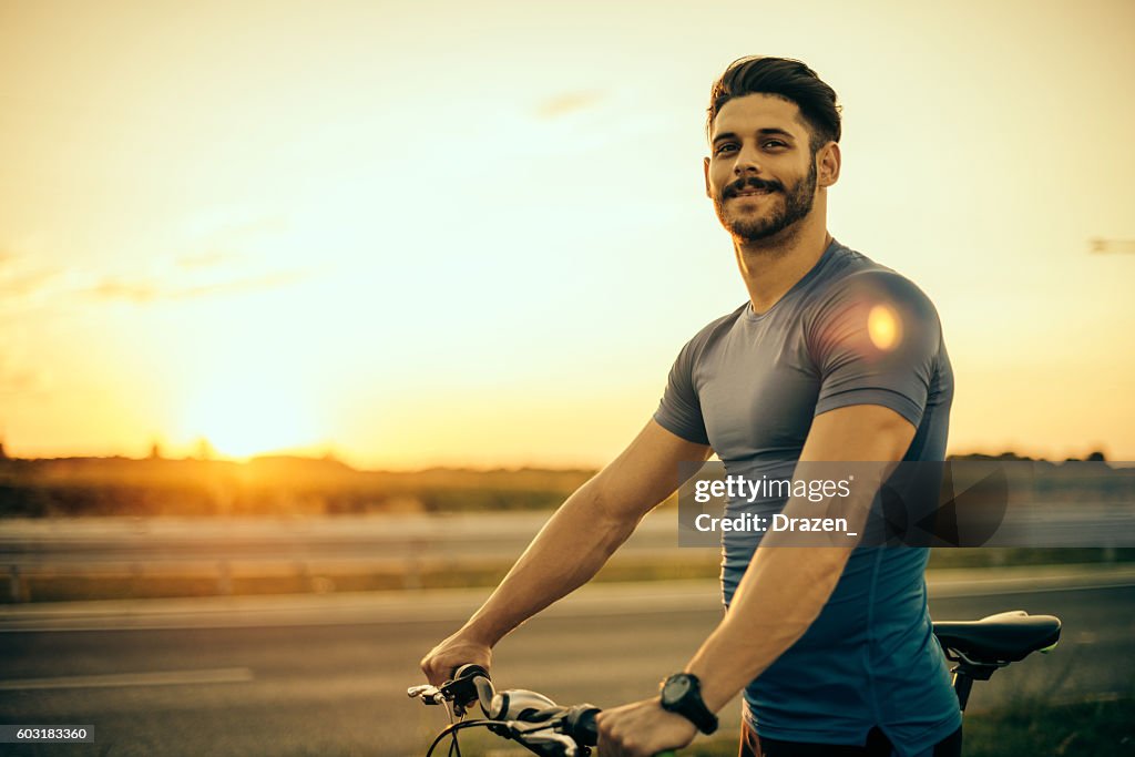 Bel ragazzo in mountain bike al tramonto