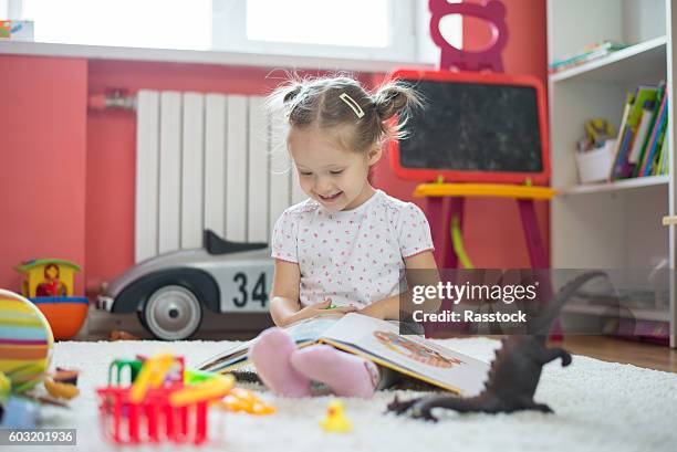 toddler girl playing and reading in the children room - nursery bedroom stock pictures, royalty-free photos & images