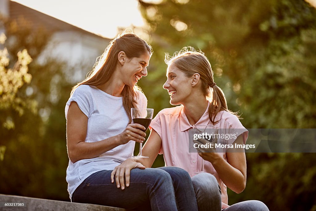 Lesbian couple holding wine glasses on patio