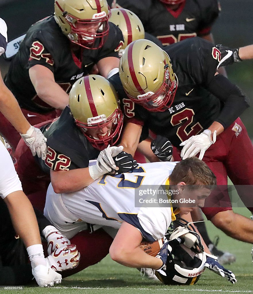 Andover High running back Joe Rockwell has his helmet ripped off as