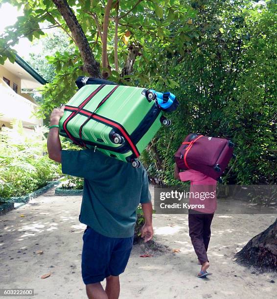 asia, maldives, view of porters carrying luggage on a tropical island - kofferband stock-fotos und bilder