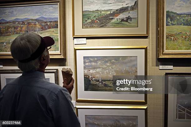 An attendee holds an ice cream cone while viewing art during the 2016 September Yearling Sale at Keeneland Racecourse in Lexington, Kentucky, U.S.,...