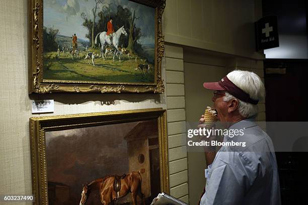 An attendee eats an ice cream cone while viewing art during the 2016 September Yearling Sale at Keeneland Racecourse in Lexington, Kentucky, U.S., on...