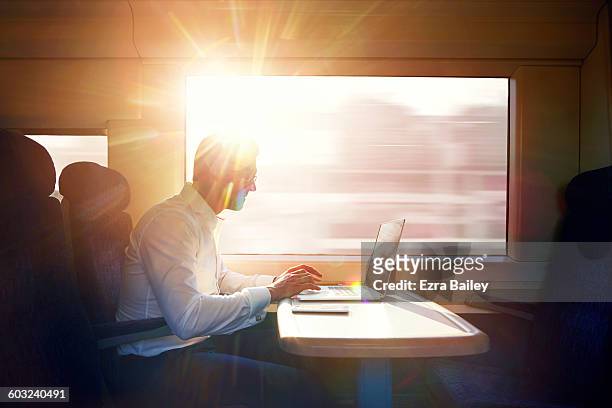 businessman working on a commuter train. - back lit people stock pictures, royalty-free photos & images