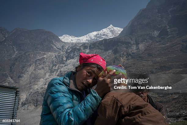 Norki Tamang holds her one year old son Pasang outside her temporary shelter in Langtang village near the pale rock wall where an avalanche of ice...