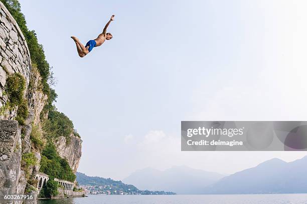 brave man diving in the water from a cliff. - high up stock pictures, royalty-free photos & images