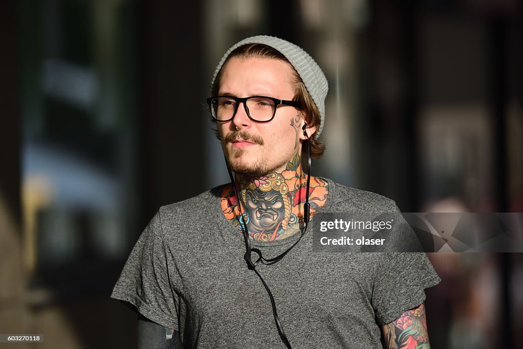 Cooler Mann mit Tattoos, Hut und Kopfhörern