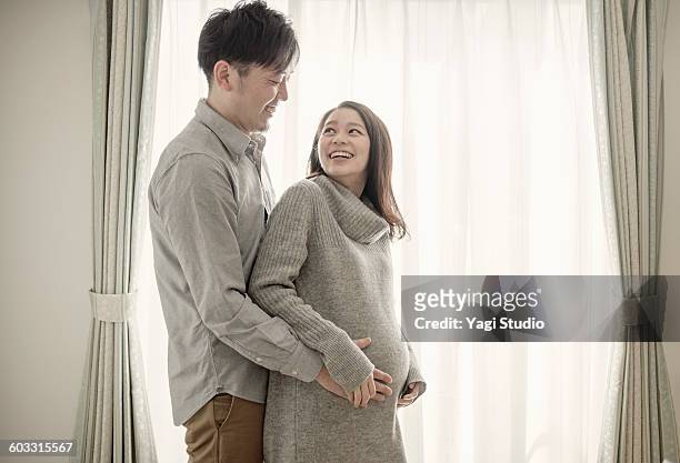 man with hand on pregnant woman's bump - the japanese wife foto e immagini stock