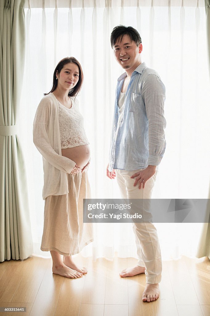 Pregnant woman and husband in front of window