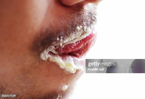 young man licking with cream in mouth,close up - schocktaktik stock-fotos und bilder