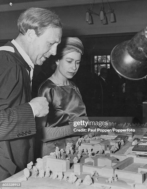 Queen Elizabeth II views a model of the proposed new University of Leicester Campus buildings with a member of University staff during a visit to...